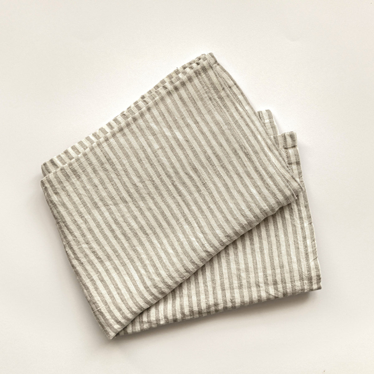 Pantry Stripe linen tea towel in grey, folded flat on a cream background